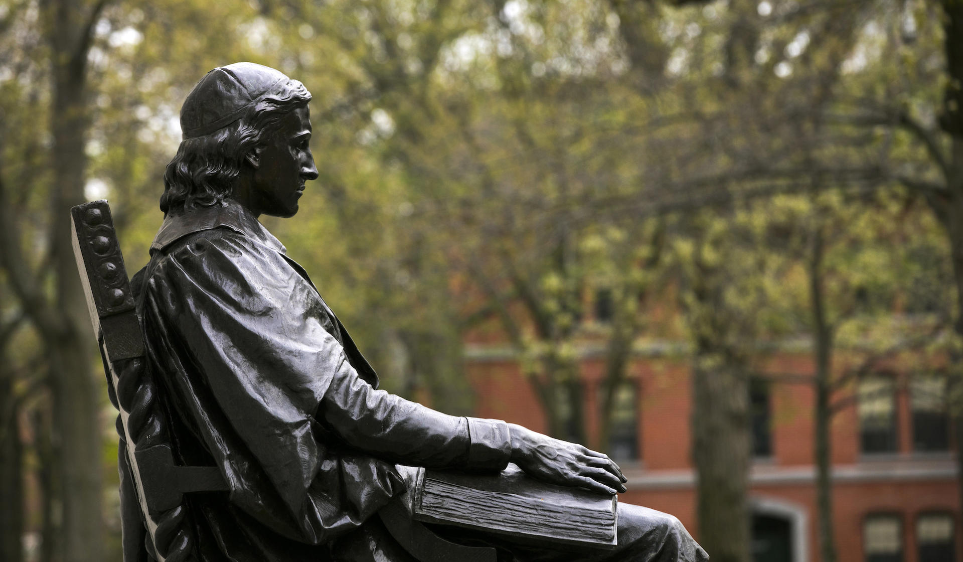 Profile of the John Harvard statue during summer in the Yard.