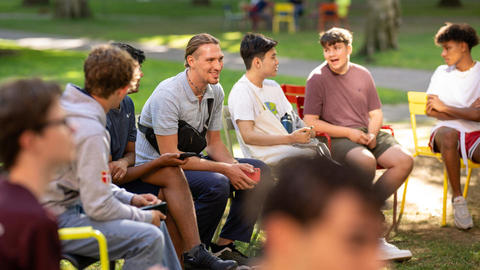 Students talking while they sit on the lawn chairs in the Yard during orientation.