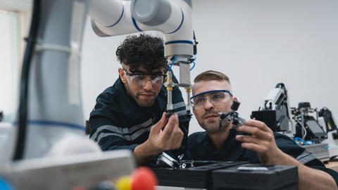 Two students work on a robotic arm