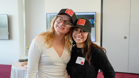 Two students pose for a photo in the PAF 20th Anniversary hats during the celebration in Smith Campus Center.