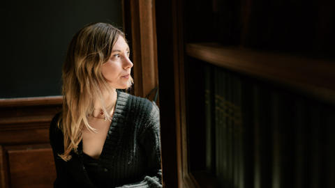 Mary Cipperman ’26 looks out of a classroom window with the sun streaming onto her face.