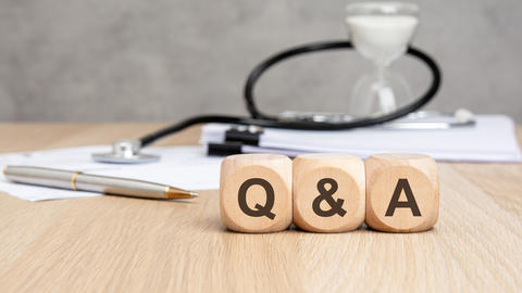 Q and A text on wooden blocks, stethoscope, hourglass and documents.