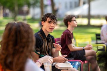 Students having conversation seated on the lawn chairs in Harvard Yard during orientation.