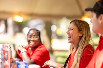 Students from the Orientation Welcoming Committee smile and welcome first-year students and families at the welcome tent during move-in.