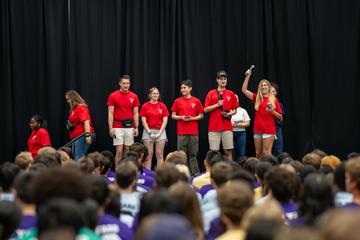 Five Orientation Welcoming Committee members stand on stage during the Crimson Kick-off orientation event in Lavietes Pavilion.