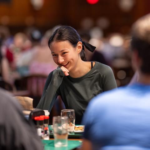 Three students enjoy a meal and a laugh at Annenberg dining hall during first-year orientation.