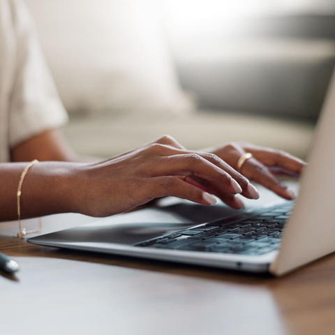 A student's hands hover over a laptop keyboard