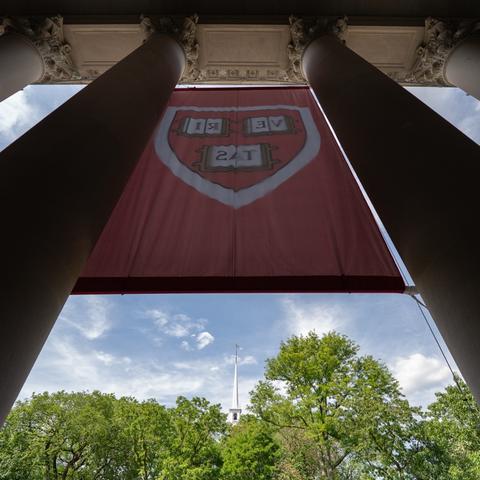 The Harvard shield on a large crimson banner between the columns in front of Widener library.