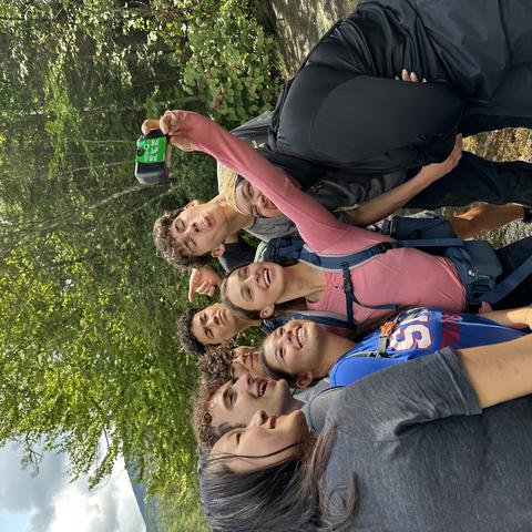Students stop to take a selfie with a disposable camera near a stream during their First-Year Outdoor Program pre-orientation trip.