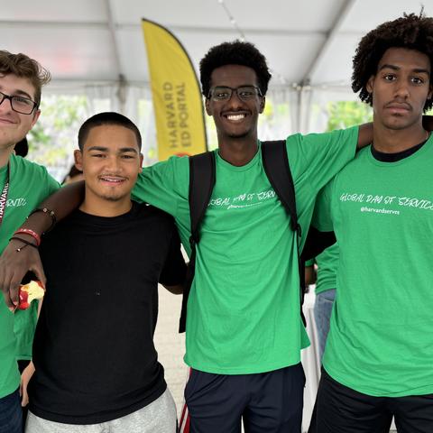 Four Harvard first-year students pose for a photo under the Science Center tent during the Global Day of Service.