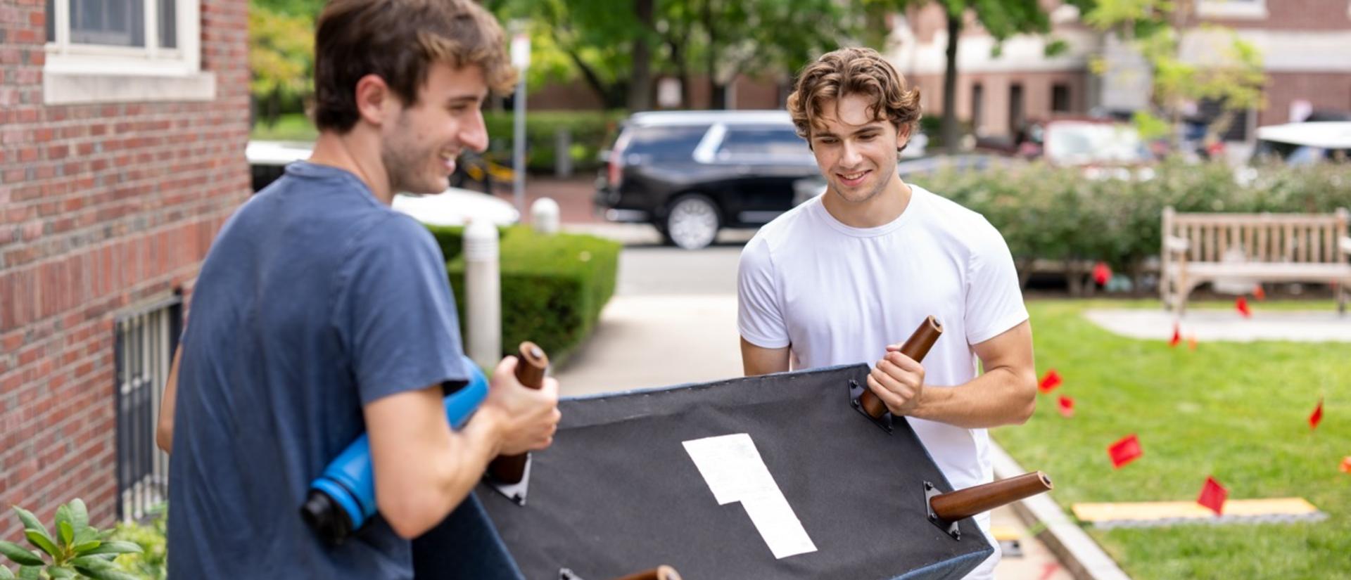 Two students moving a piece of furniture into a first-year dorm.