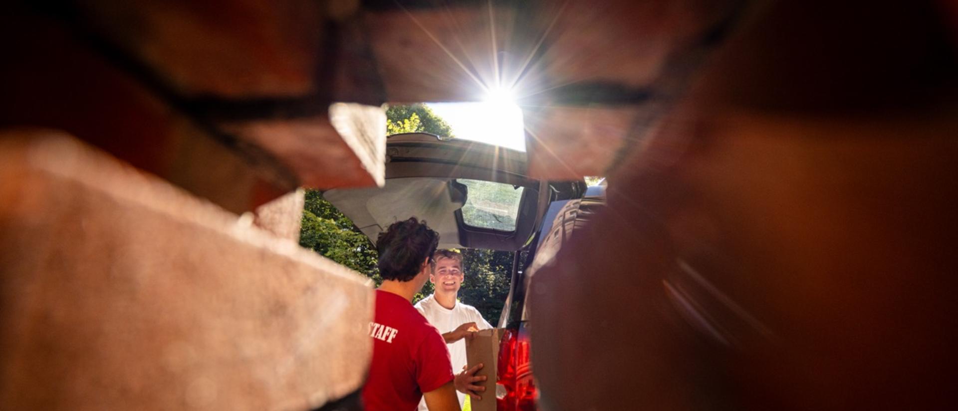 A first-year student unloads his car with the help of residential staff during first-year move-in.