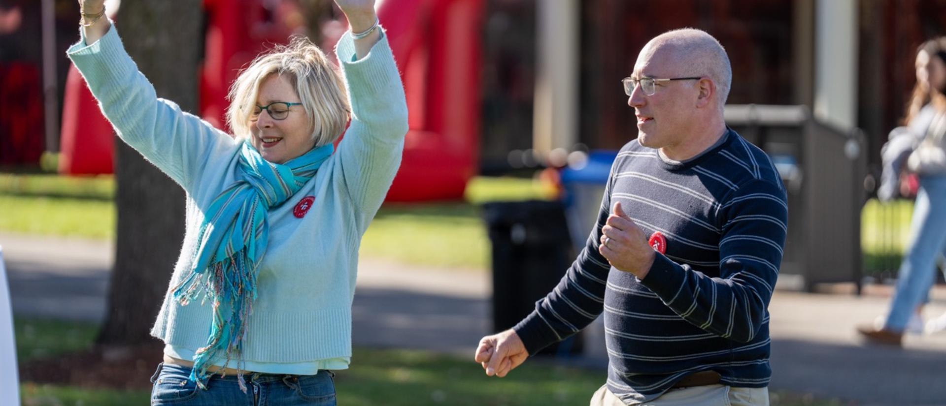 Two family members dance on the Athletics lawn during Family Weekend.